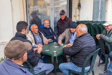 1 Nisan 2023. İtalya, Calabria, Pizzo. Restoranın dışında kağıt oynayan bir grup adam..