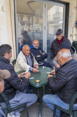 1 Nisan 2023. İtalya, Calabria, Pizzo. Restoranın dışında kağıt oynayan bir grup adam..