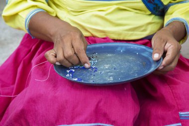 El işi için küçük boncukları sıralayan bir kadının yakın çekimi. Meksika, Nayarit Eyaleti, Bucerias.