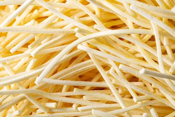 The texture of Italian raw pasta as a background. A close shot of pasta. Macro photo. Raw Italian pasta. Close-up.