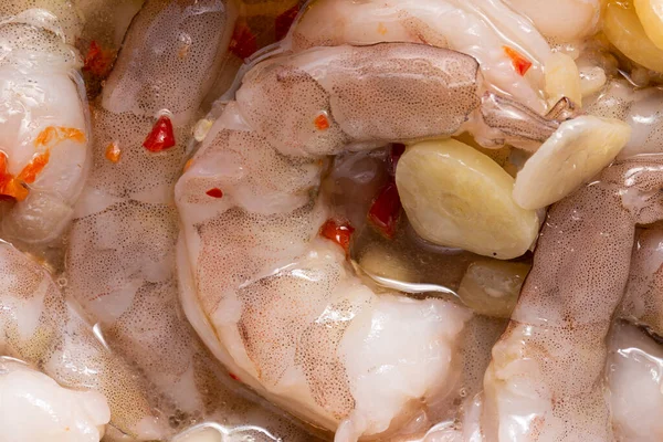 The texture of raw shrimps as a background. A close shot of raw shrimps. Macro photo. Marinated shrimps with chilli and garlic.