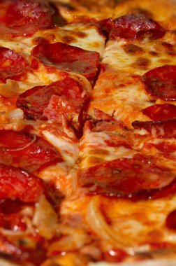 Arka planda soğanlı salamlı pepperoni pizza. Pizzanın yakın çekimi. Makro fotoğraf. Biberli salamlı pizza, soğanlı..