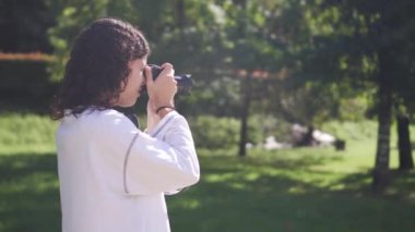 Beyaz kazaklı genç esmer kız telefoto kamerasıyla doğal ortamdaki vahşi hayatı çekiyor. Yüksek kalite 4k görüntü