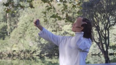 Beyaz kazaklı beyaz esmer kız cep telefonuyla gülümseyen bir selfie çekiyor. Yüksek kalite 4k görüntü