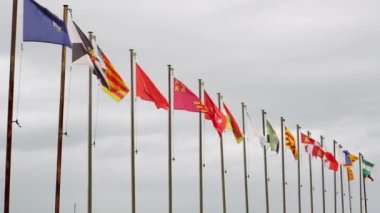 İspanya Krallığı 'nın özerk topluluklarının direkleri olan otantik bayraklar bulutlu bir gökyüzünde güçlü bir rüzgarda sallanıyordu. Endülüs, Aragon, Asturias, Islas Baleares, Canarias, Cantabria