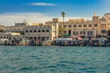 Dubai, Birleşik Arap Emirlikleri. 13 Şubat 2025. Dubai 'deki eski bina ve rıhtımlarda insanlar ve palmiye ağaçları görülür.