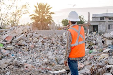 Worker with helmet and safety vest from behind. debris zone