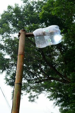 Bambu direkleri üzerindeki sokak lambalarının büyüleyici görüntüsü sabahın erken saatlerinde hala parlıyor. Yağmur yağmasın diye değiştirilmiş galon su şişesi kapaklarıyla korunuyor..