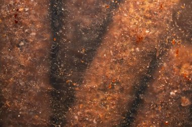 Kurutulmuş çikolatalı aperatifin şeffaf ambalajının yakın çekimi. Plastiğe yapışan kırıntılar ve çikolata lekeleri görüntüye doku ve derinlik katan soyut, bulanık bir desen oluşturuyor..