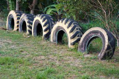 Yenilenmiş lastikler, sırayla boyanmış ve düzenlenmiş, hem bahçe çiti hem de oturma alanı olarak hizmet veriyor. Dış mekanlarda yaratıcılık ve çevre dostu tasarım sergilemek için mükemmel..