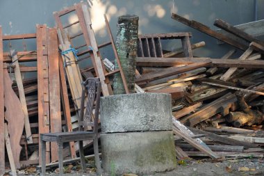 Geri dönüşümü bekleyen bir odun yığınının yanında, açık bir alanda tahta bir sandalye. Herhangi bir ayara kırsal bir dokunuş eklemek ve sürdürülebilir uygulamaları vurgulamak için mükemmel.