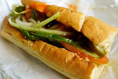 Yumuşak ekmek dilimlerinin arasına yerleştirilmiş salatalık, dolmalık biber, domates ve soğan da dahil olmak üzere lezzetli bir sandviç, keskin ve taze lezzetlerin mükemmel bir karışımını sunuyor..