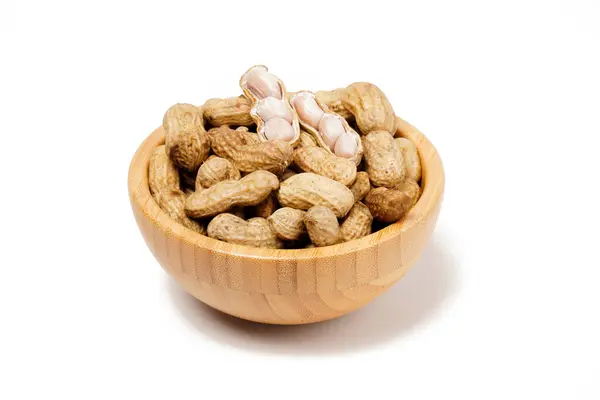 Haşlanmış fıstıkla (Arachis hipogaea) dolu ahşap kase, aperatif olarak mükemmel, beyaz arka planda fotoğraflanmıştır..