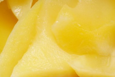 Genç mango kickshaw, ince dilimlenmiş sarı mangodan yapılmış, ahşap bir tabağa yerleştirilmiş, beyaz bir arka planda fotoğraflanmış..