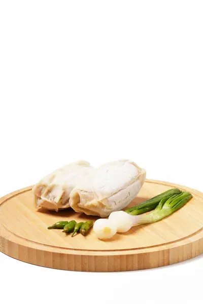 Bambu filizleriyle dolu iki donmuş lumpia ve beyaz ambalajlı, kızarmaya hazır et. Yeşil biber ve soğan ile servis edilir, yuvarlak bir ahşap tepside beyaz arka planda fotoğraflanır..