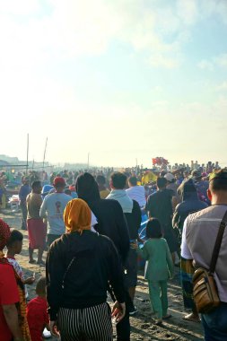 Yogyakarta, Endonezya - 18 Ağustos 2024: Her yaştan insan, siyah kumsala vuran güçlü dalgalarla Depok Beach, Yogyakarta, Endonezya 'daki sabah atmosferinin tadını çıkarıyor.