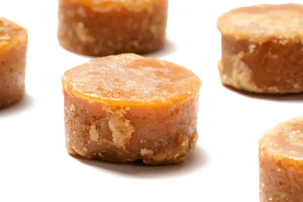 stock image A neatly arranged stack of traditional brown sugar (gula jawa) cylindrical blocks isolated on a clean white background. The rich, caramel color contrasts beautifully with the crisp, minimalist backdrop