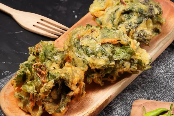 Kızarmış ıspanak, hamurla kaplanmış büyük ıspanak yaprakları ve altın mükemmelliğinde kızartılmış, meze ya da aperatif olarak mükemmel. Karanlık bir arka planda çekilmiş. Amaranthus olarak da bilinir..