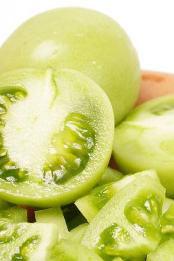 Beyaz arka planda tam ve dilimlenmiş yeşil domatesler (Solanum lycopersicum). Fotoğraf, dilimlerin taze, sulu ve taze dokusunu yakalıyor..