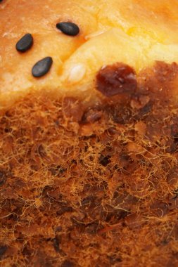 Üzerine susam tohumu ve her iki tarafına da öğütülmüş et ipliği sürülmüş yumuşak ve lezzetli ekmek. Beyaz bir arkaplanda çekilmiş, nefis desenli bir görüntü sunuyor..