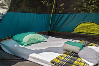 Ormandaki bir çadırın içindeki şilte, yastık, çarşaf ve havluları kapat.