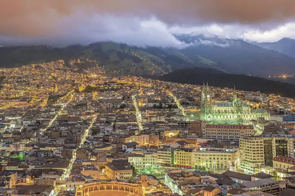 Sömürgeci eski Quito kasabasının altın saatindeki panoramik manzara Ulusal Yeminin Basiliğinin eteğinde ve Belmonte Plaza de Toros 'un ön planında yatıyor.