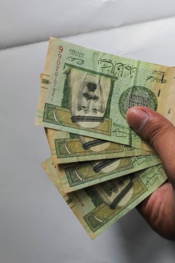 Jakarta, Endonezya 15 Kasım 2022: Beyaz arka planda Suudi Arabistan 'ın el ve cüzdanı 1 riyall banknotunda