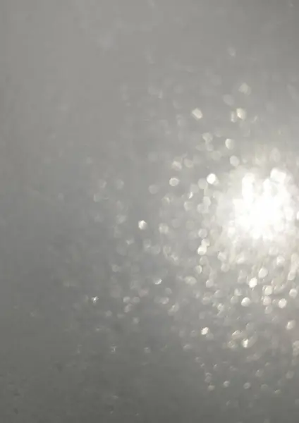 Gri arka planda beyaz ve gümüş parıltılı bokeh. Noel tatili geçmişi