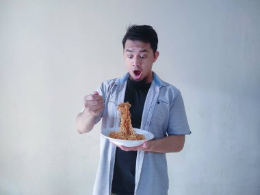 Asyalı genç adam kızarmış eriştenin tadını çıkarıyor. Öğle yemeği konsepti.
