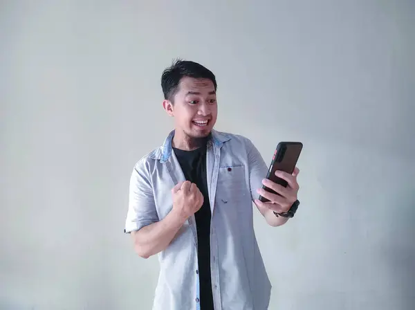 Reifer Asiatischer Mann Hält Ein Mobiltelefon Ballt Die Faust Und — Stockfoto