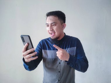 Şaşkın ve mutlu bir yüzle cep telefonu tutan genç bir Asyalı.