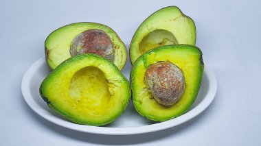 Alpukat veya Avokado 'nun yarısı (Persea americana), olgun ve taze, beyaz tabakta servis edilir.