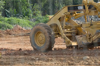 Bir Tırtıl makinesi toprak bir yolda. Makine sarı ve büyük bir lastiği var.
