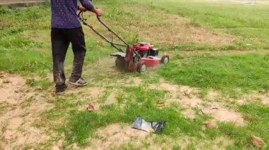 Kolkata 'da bir tarlada elektrikli çim biçme makinesiyle çim biçen bir adamı yakından çek. Kolkata Oyun Alanı.