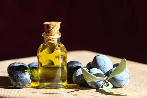olive oil in a bottle and black olives on wooden table