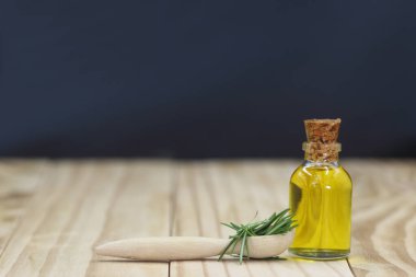 Koyu arkaplandaki ahşap masada zeytinyağı ve biberiye. Metin için boşluk.