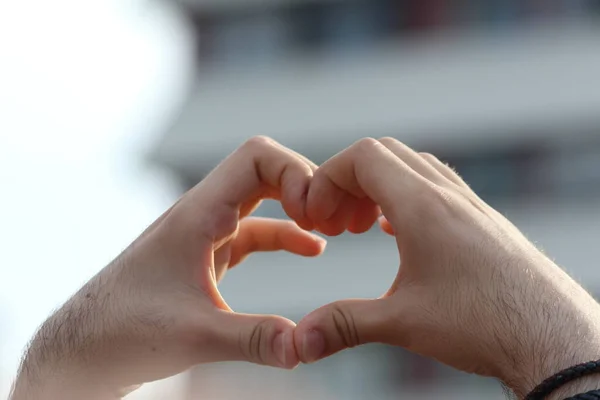 a young man gesturing heart hand