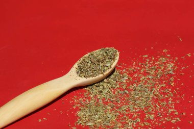 Ahşap bir kaşıkta kırmızı arka planda bir bitki.