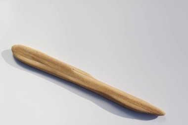 Beyaz arkaplanda nehir tarafından şekillendirilmiş tahta çubuk