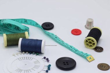 İplik makaraları, düğmeler, beyaz arkaplanda dikiş iğnesi