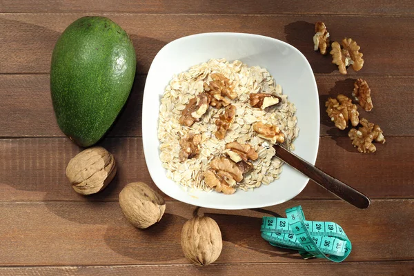 healthy breakfast. oatmeal, avocado, nuts on white wooden background. top view.
