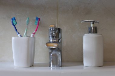 Temiz hijyen ürünleri ve aksesuarlarla dolu bir banyo. Diş fırçası ve sıvı sabun makinesi banyoda.