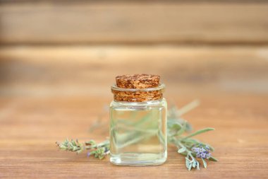 Ahşap zemin üzerinde cam şişe içinde lavanta yağı