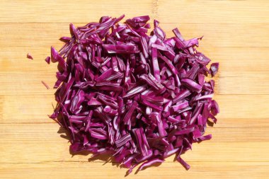 Kesme tahtasının üzerinde ince doğranmış kırmızı lahana.