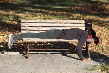 Parktaki bankta uyuyan evsiz bir adam.
