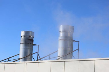 Havalandırmasından çıkan buharla ısıtma ünitesi mavi gökyüzünün arka planına çarpıyor.