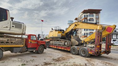 Kazı makinesi inşaat alanındaki kamyonlara yüklendi.