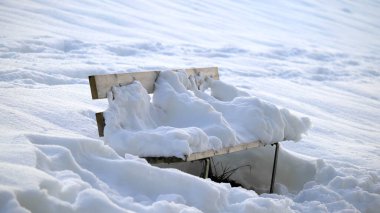 Kışın karla kaplı tahta bir bank.
