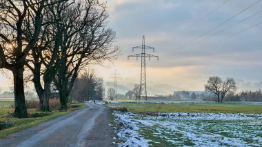 Kışın yanında ağaçlar ve arka planda elektrik direği olan kır Raod 'u