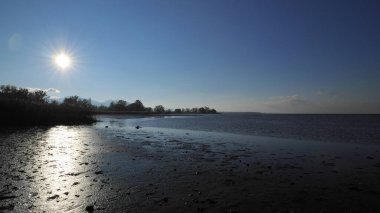 Constance Gölü 'nde akşam güneşi Islak kumda güneş ışınları